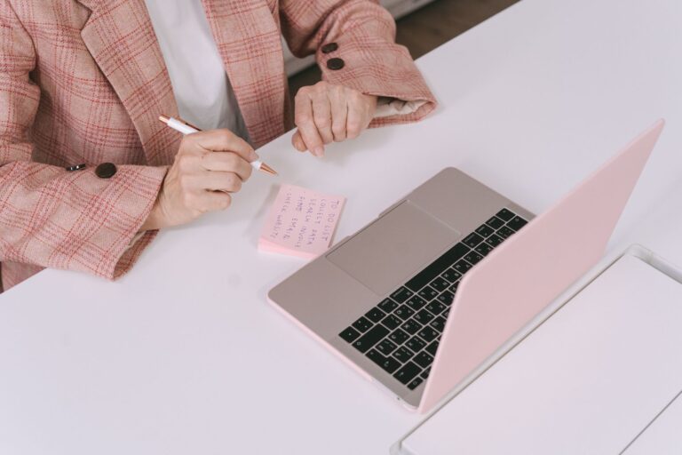 Person vergleicht am Schreibtisch Produktangaben auf dem Laptop mit eigenen Notizen