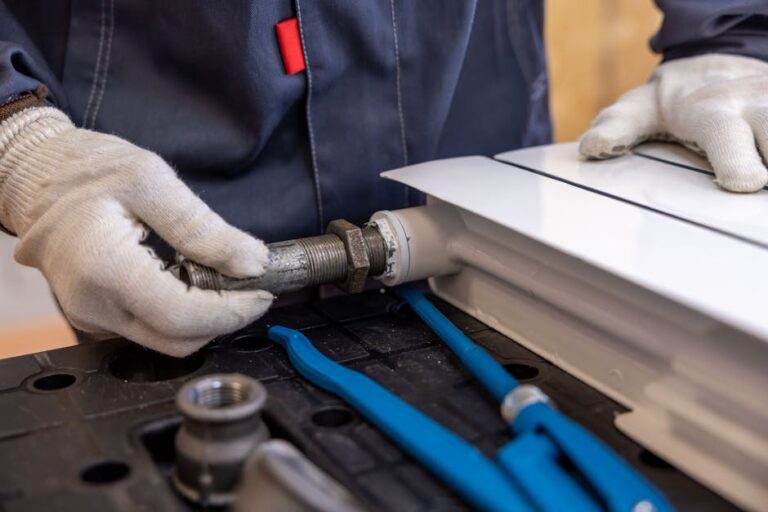 selfio - Close-up of a plumber installing a radiator pipe using specialized tools.